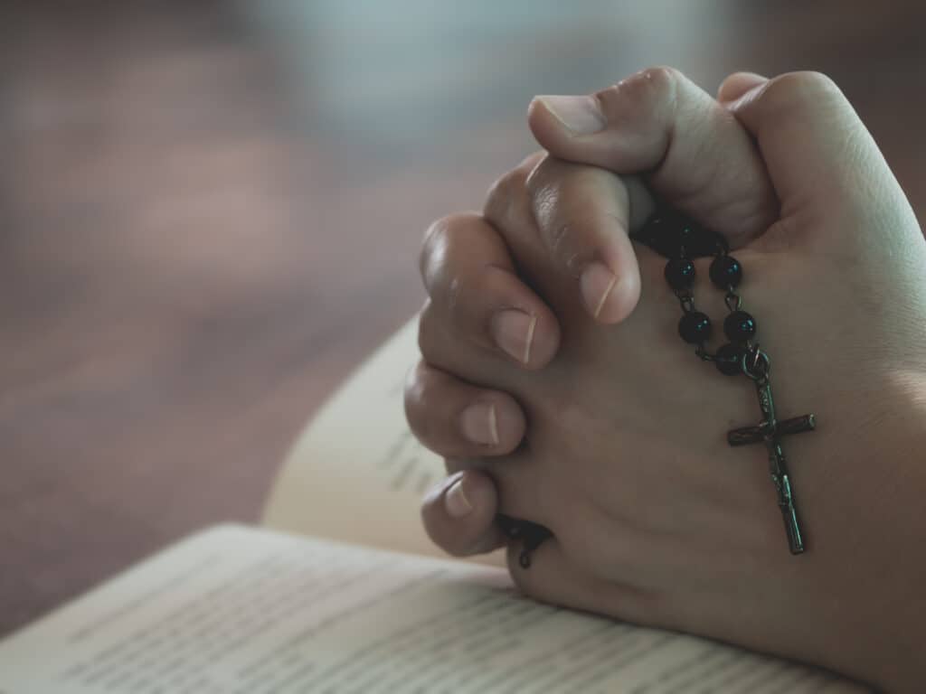 Hand of woman praying for christian religion with blurred background , Casual woman praying with her hands together over a opened Bible.