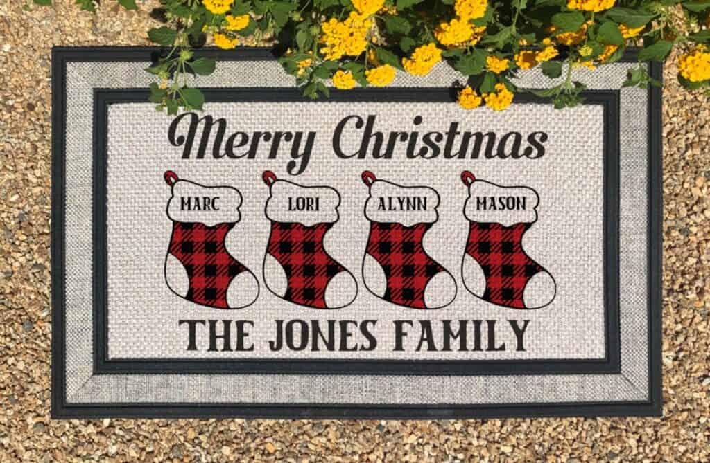 A sign that says \"Merry Christmas. The Jones Family.\" featuring Christmas stockings with children\'s names on them.