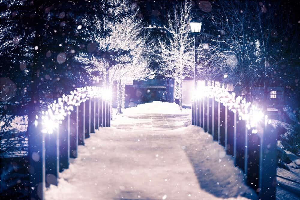 A lit-up bridge covered in snow at night.