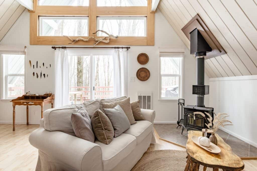 A living room with a neutral color palette. Large windows let in lots of natural light. 