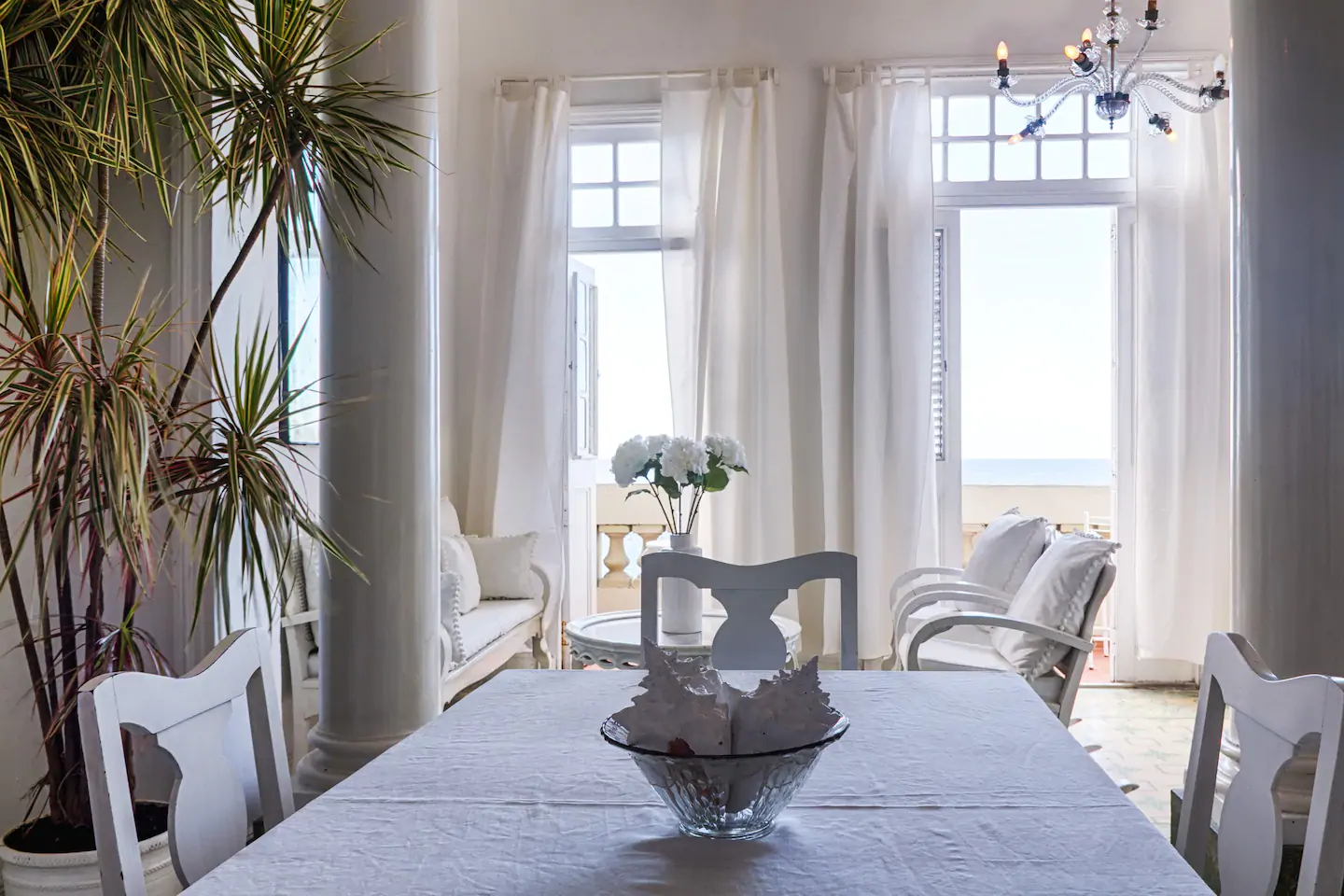 An empty table with a view of the beach through the window.