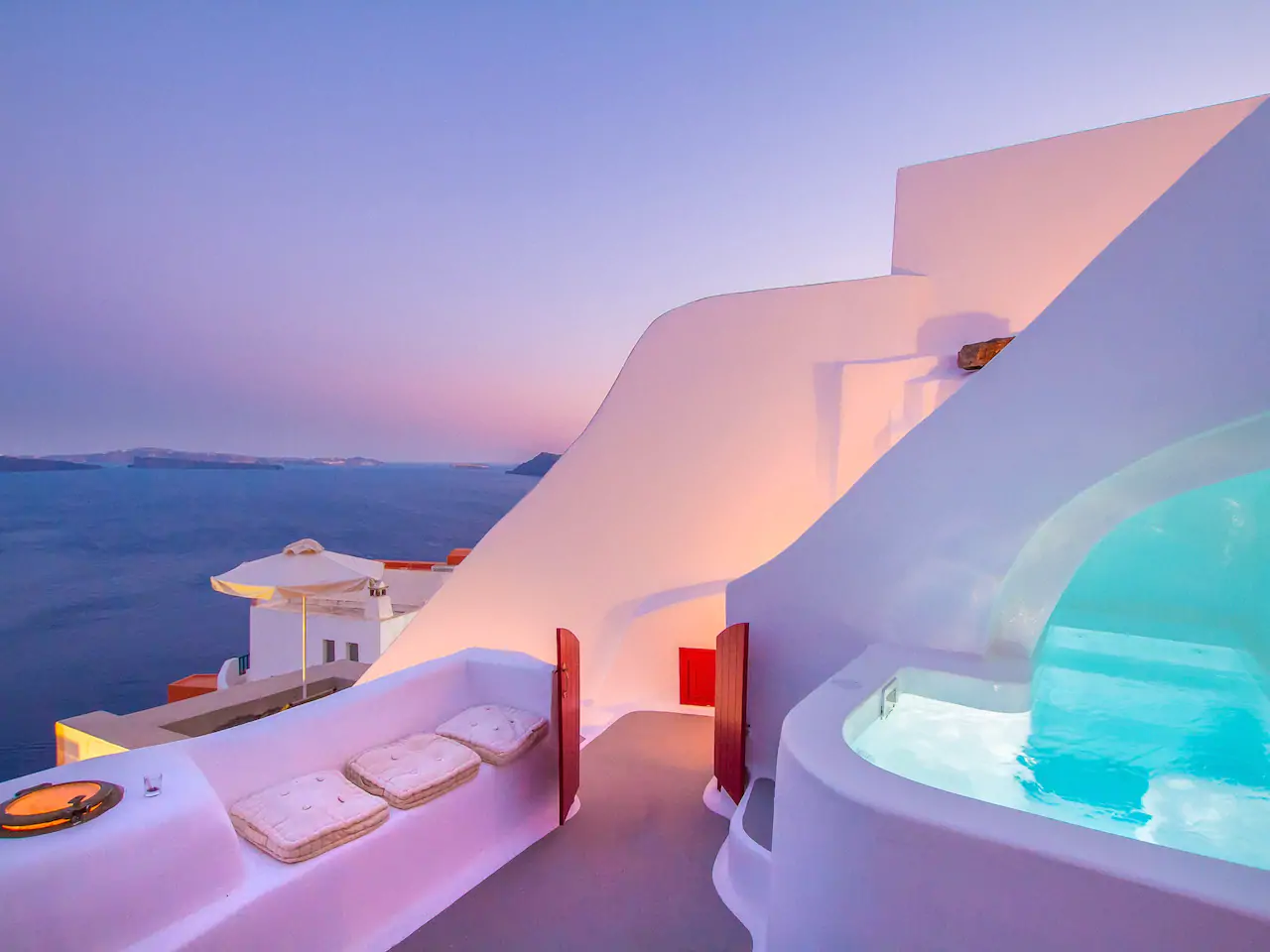 A white building next to the ocean at sunset under a purple sky. 