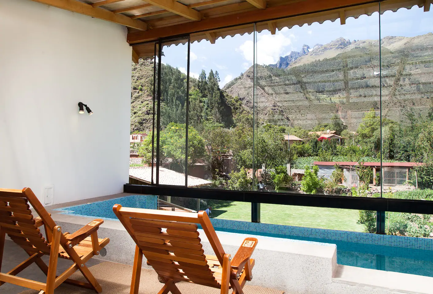 Wooden chairs sitting next to a pool looking out to a view of mountains.