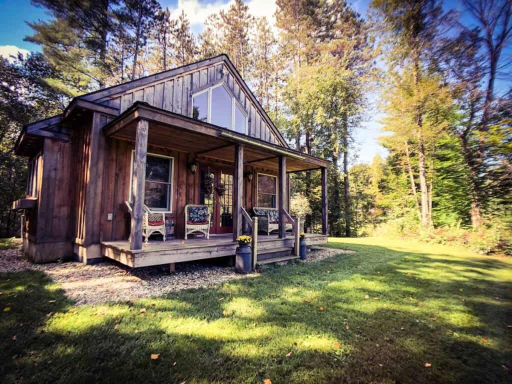 A small charming wooden cabin with a porch in a forest.