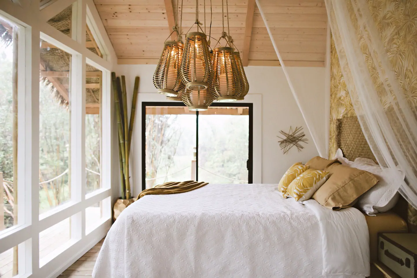 Bright and airy bedroom with a bed that has white bedding and yellow throw pillows. 