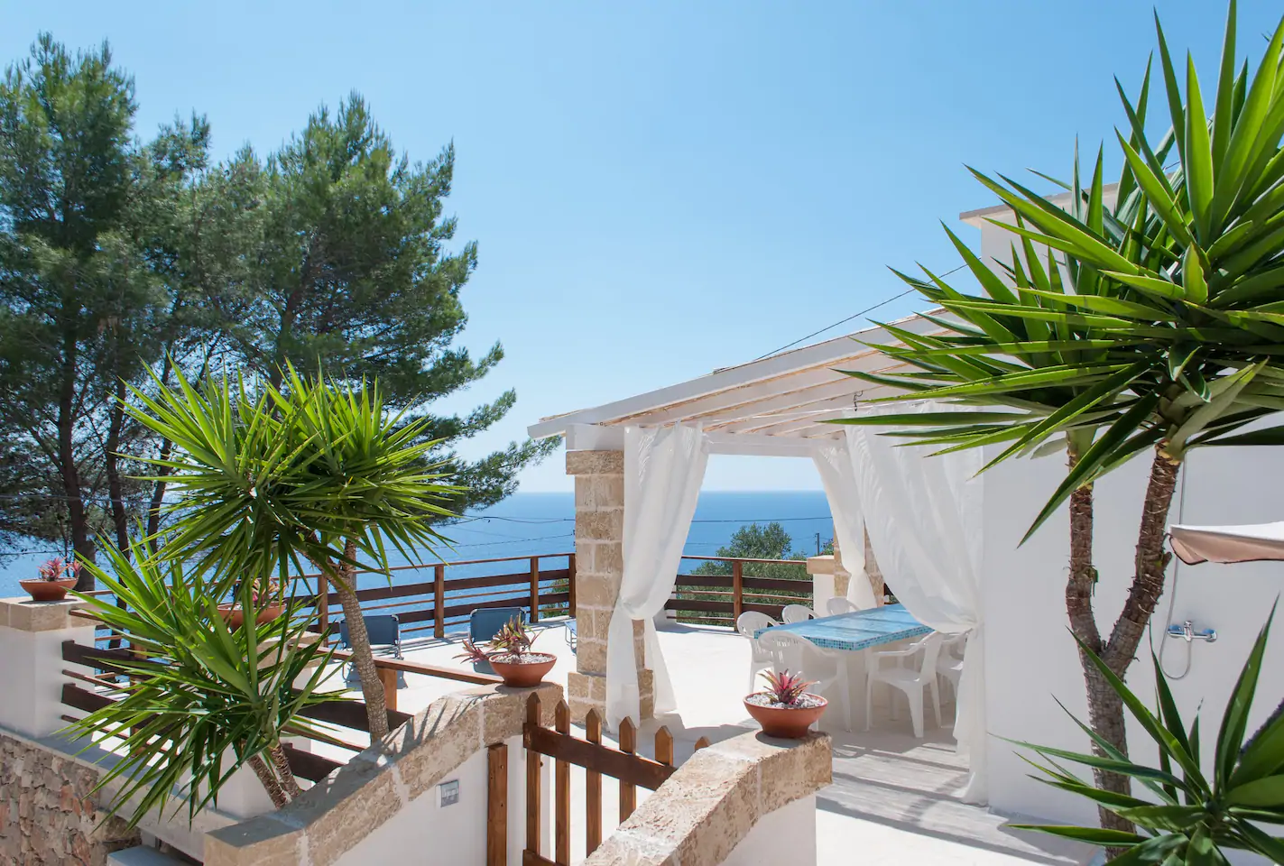 Empty white deck with table and chairs next to the ocean.