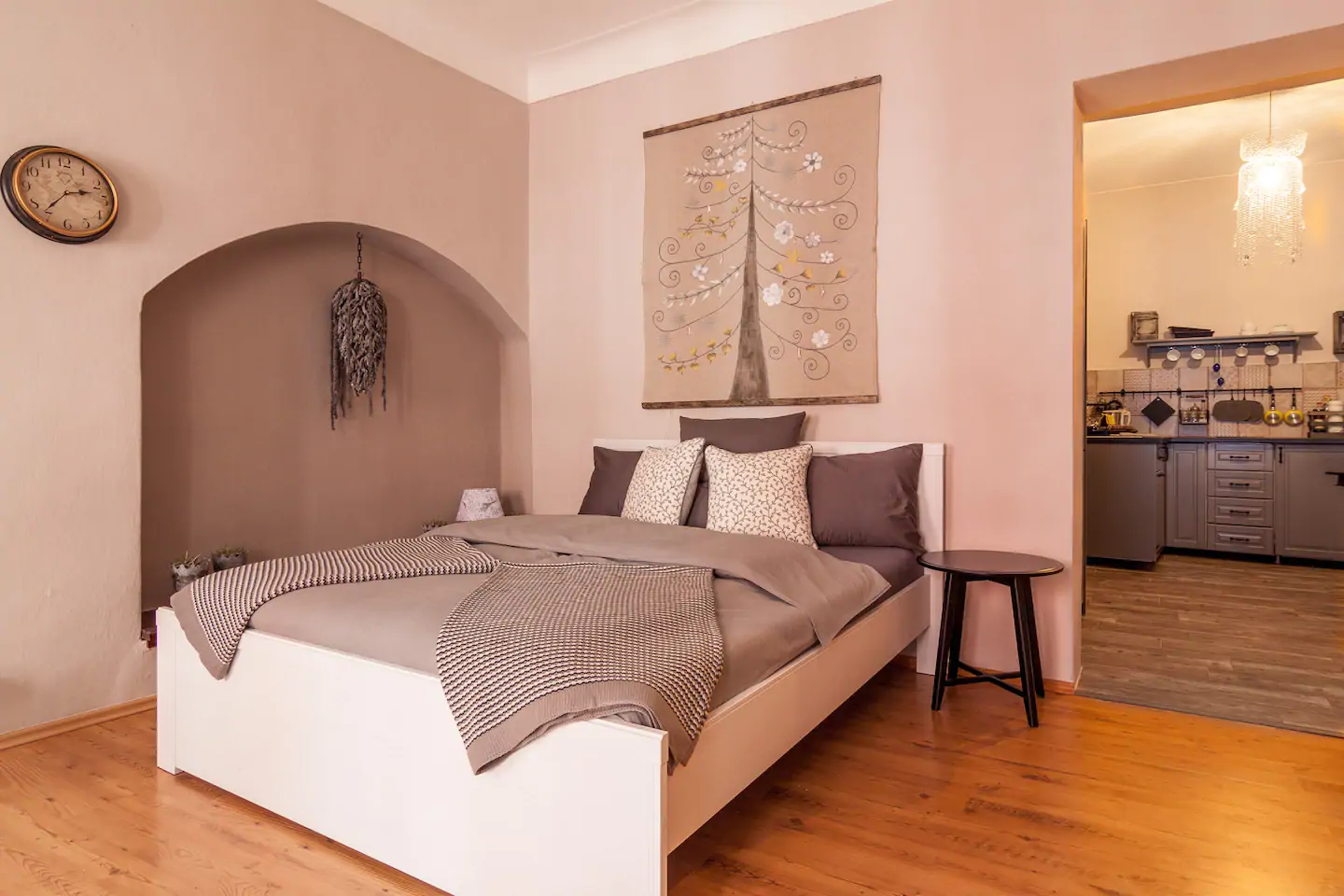 Comfortable bed with grey bedding. Above the bed is artwork of a tree.