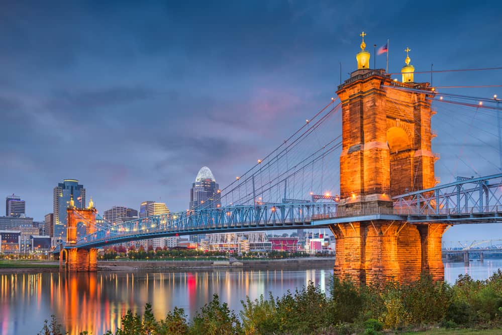 A bridge stretches across a body of water at night under a purple sky.