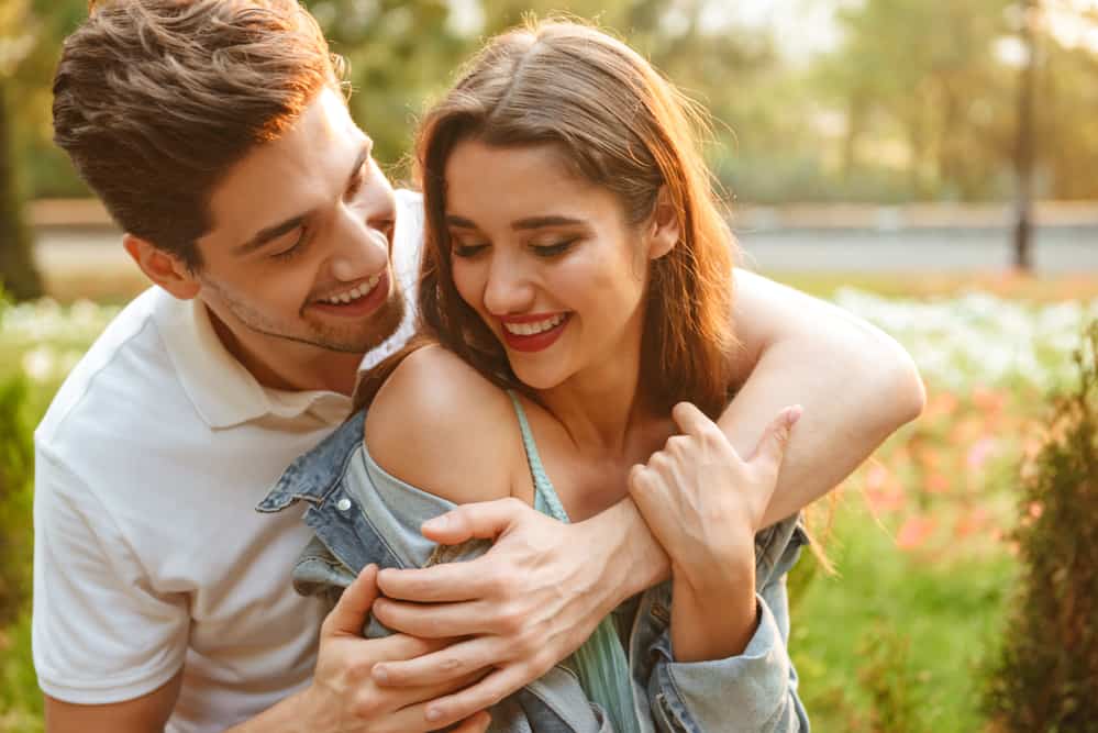 Image of happy young loving couple walking outdoors while hugging.