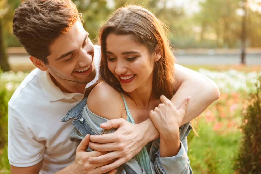 A young happy couple in love hugs outdoors.