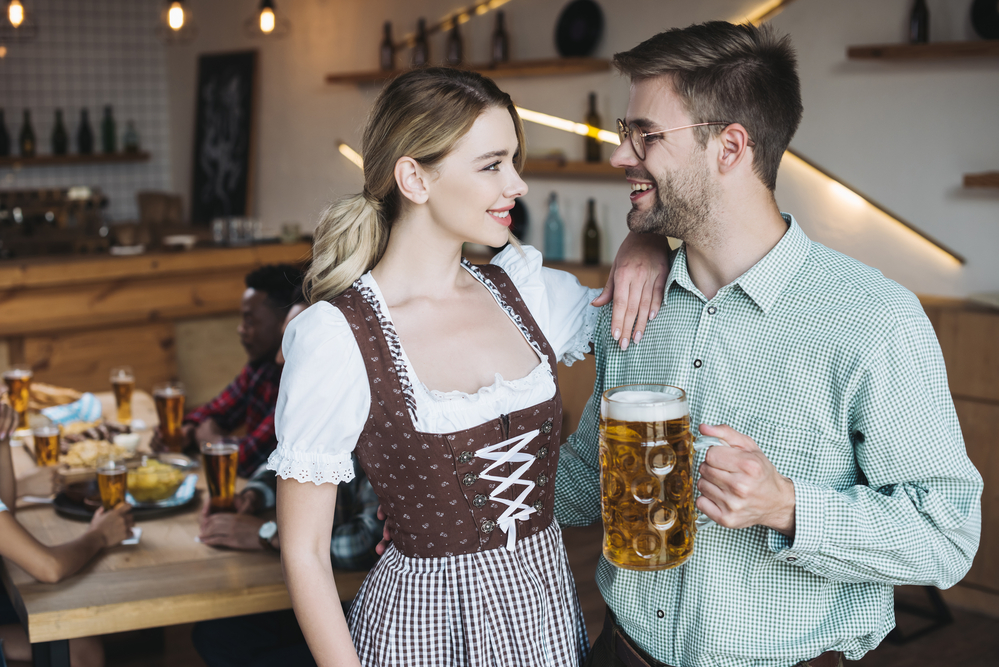 A man and woman smiles at each other while holding a big pint glass.