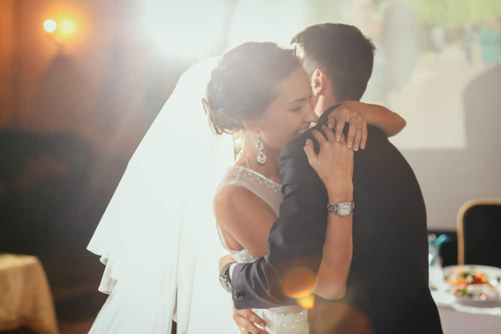 A wedding couple embraces with smiles on their faces.