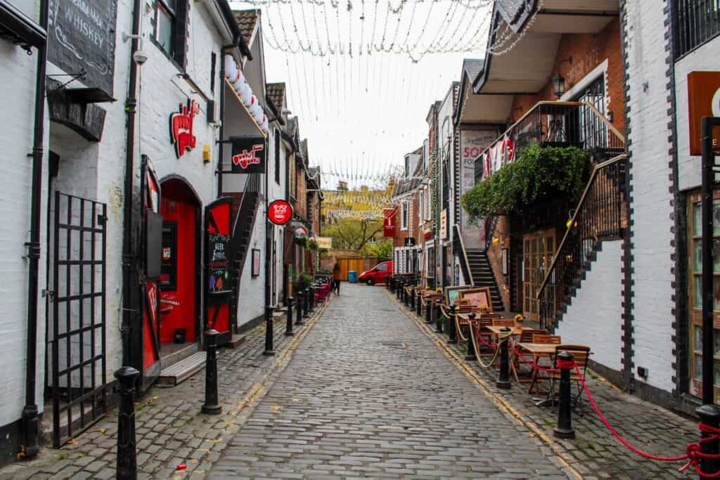 A cobblestone street lined by white buildings with red accents. 