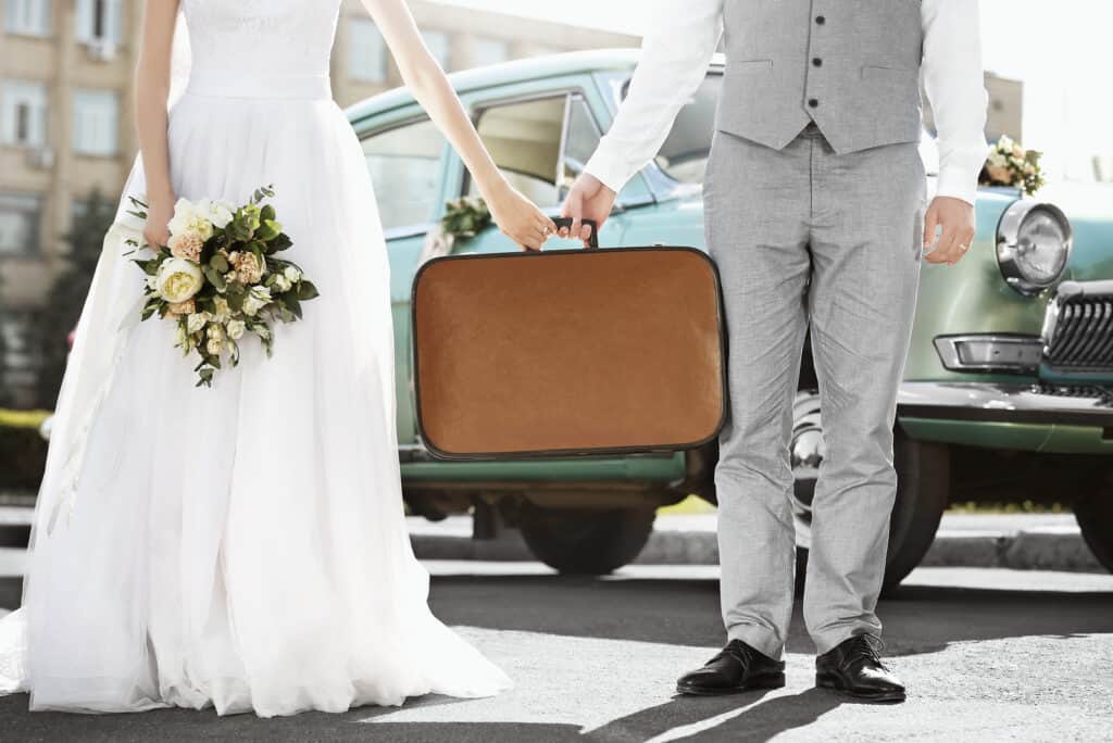 Close up of a man and woman in wedding clothes holding a briefcase.