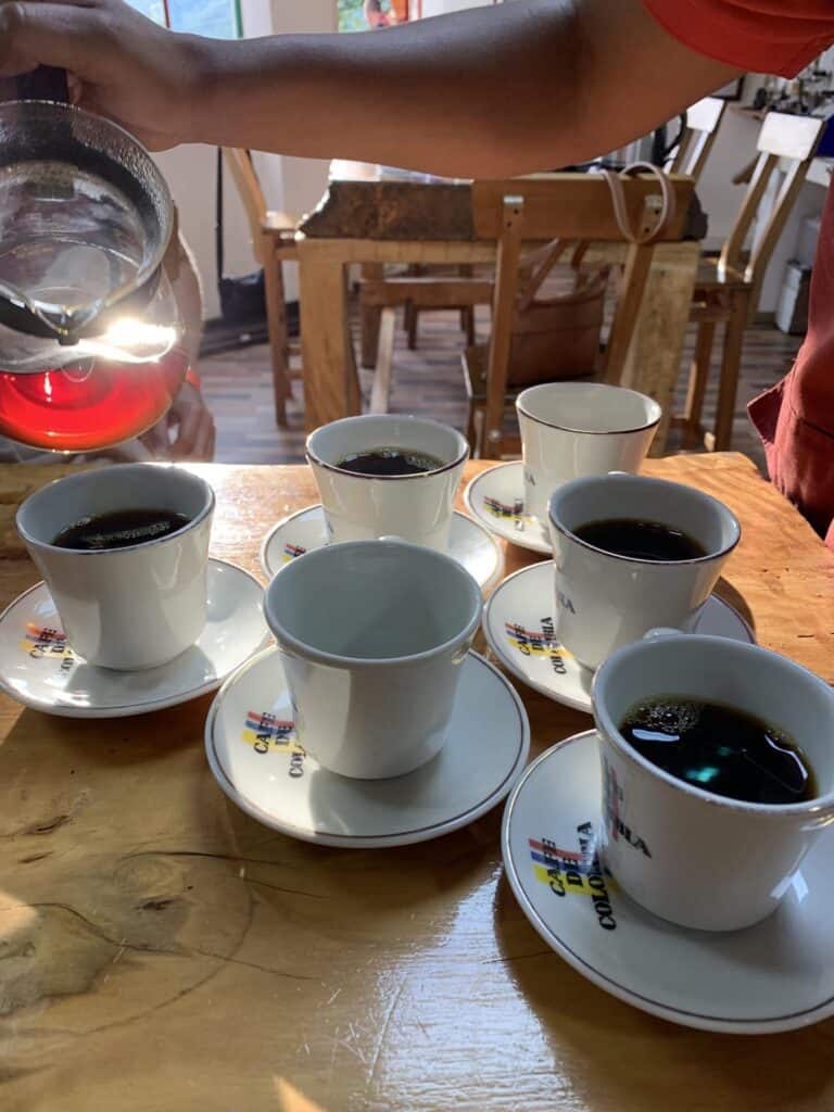 Multiple cups of coffee in small white cups on a wooden table.