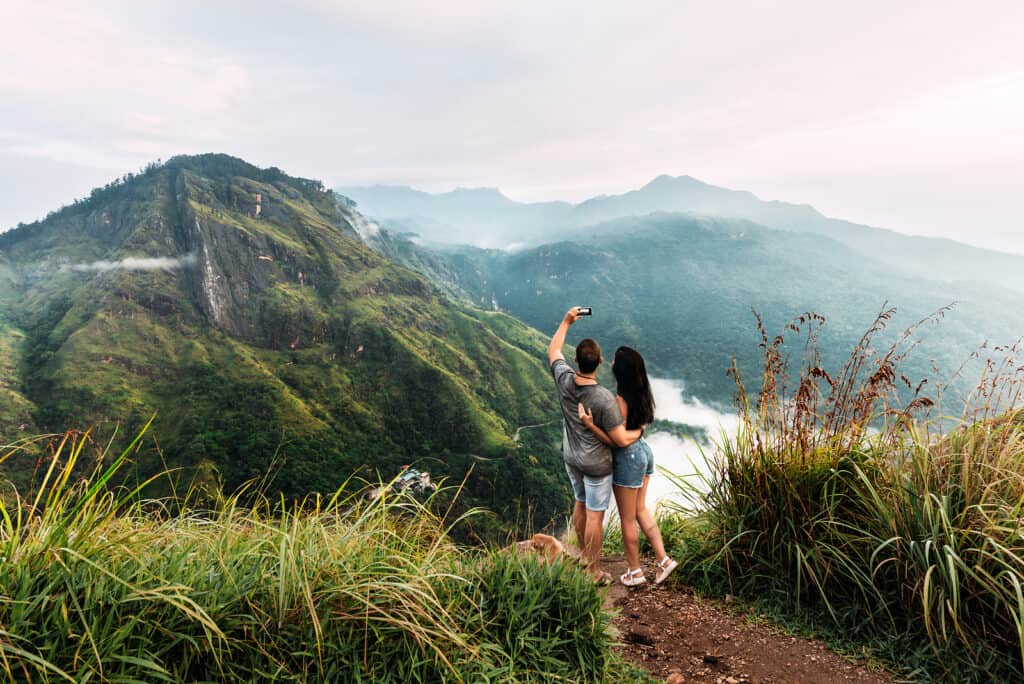 A man and a woman take a selfie in mountainous scenery.