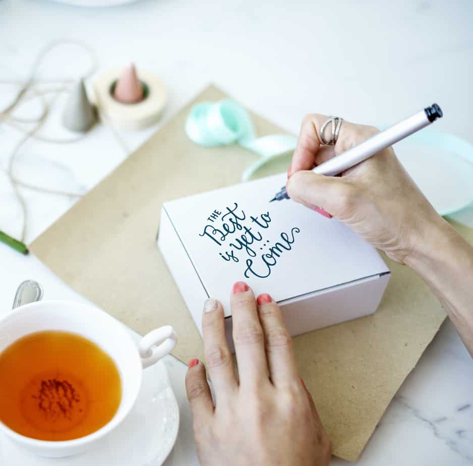 A person writes a message on a white box.