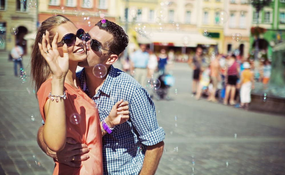 A couple is blowing bubbles together outside.