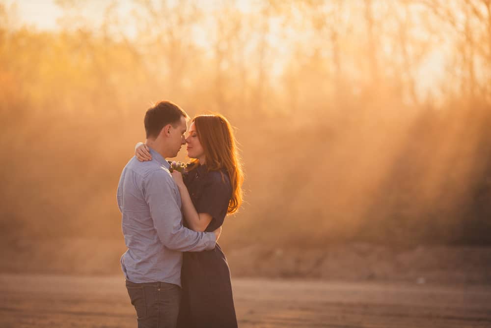 A couple embraces while standing on the road in the dust.