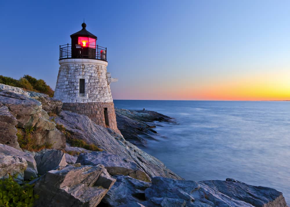 A lighthouse at sunset on a rocky coast.