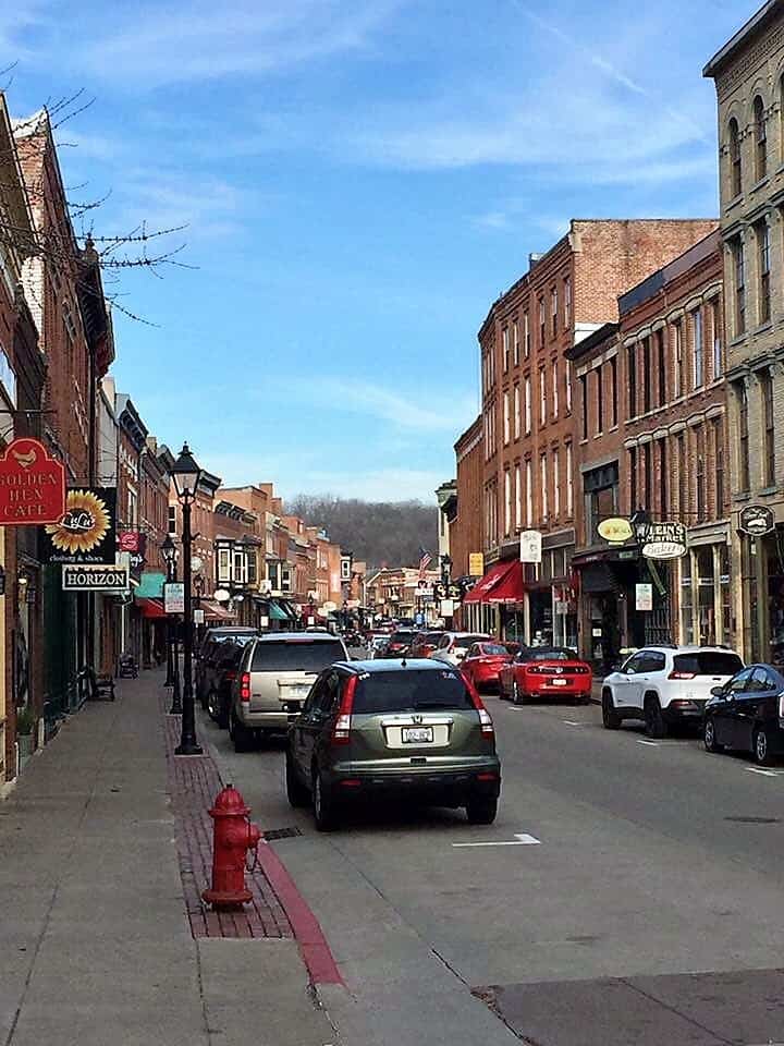 Cars are parked along a busy street lined with storefronts.