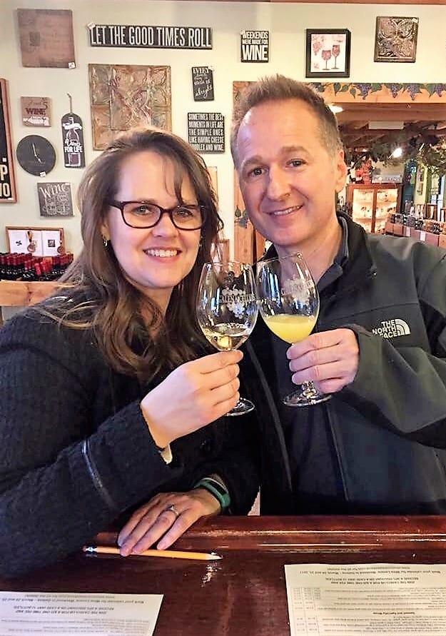 A man and woman smile while toasting their glasses in a restaurant.