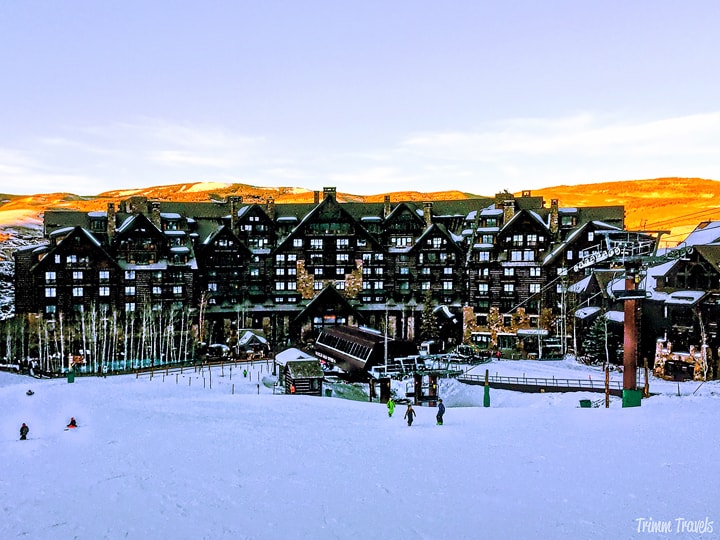 Snowy mountain slopes leading down to a massive ski resort. 