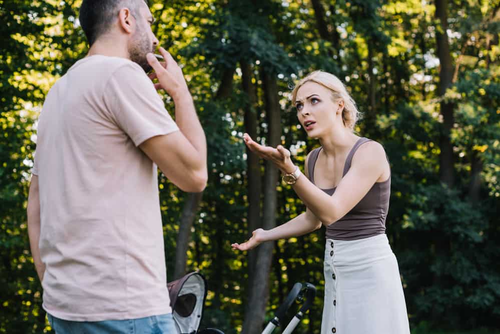A man and woman argue in the woods.