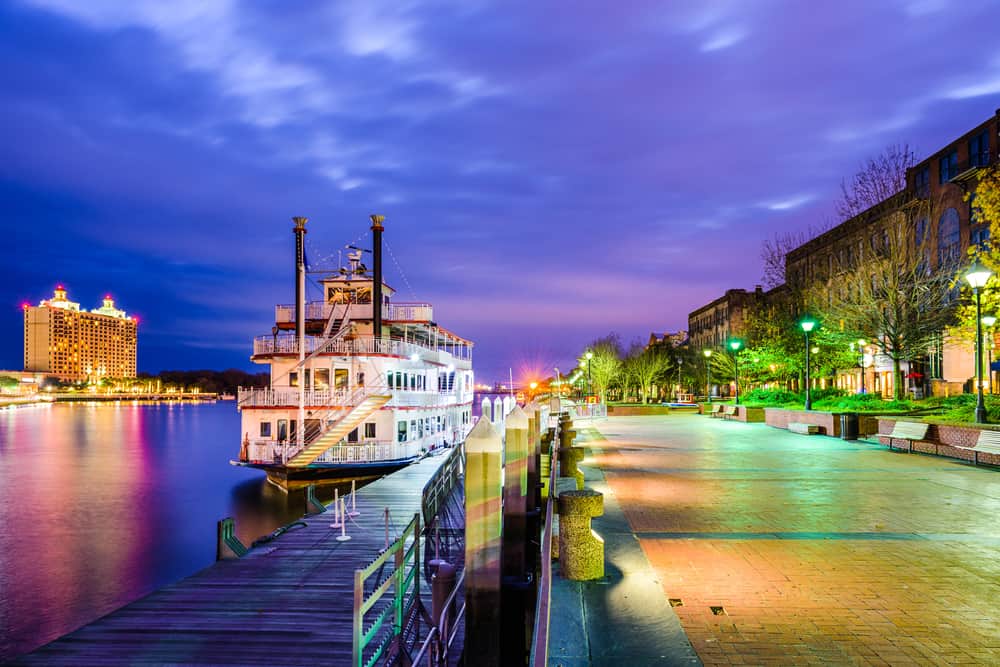 A boat floats on the water next to a dock under a purple sky.