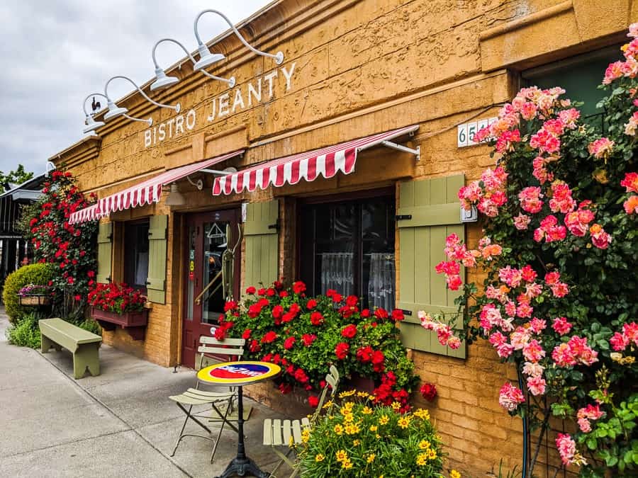 Table and chairs outside a tan building that says Bistro Jeanty.