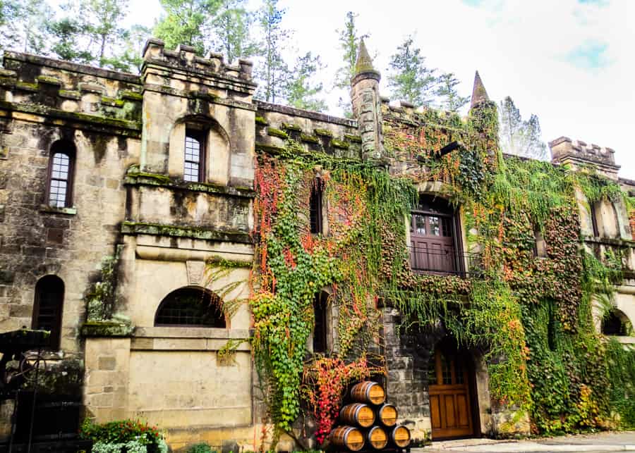 A large stone building covered in greenery and vines.