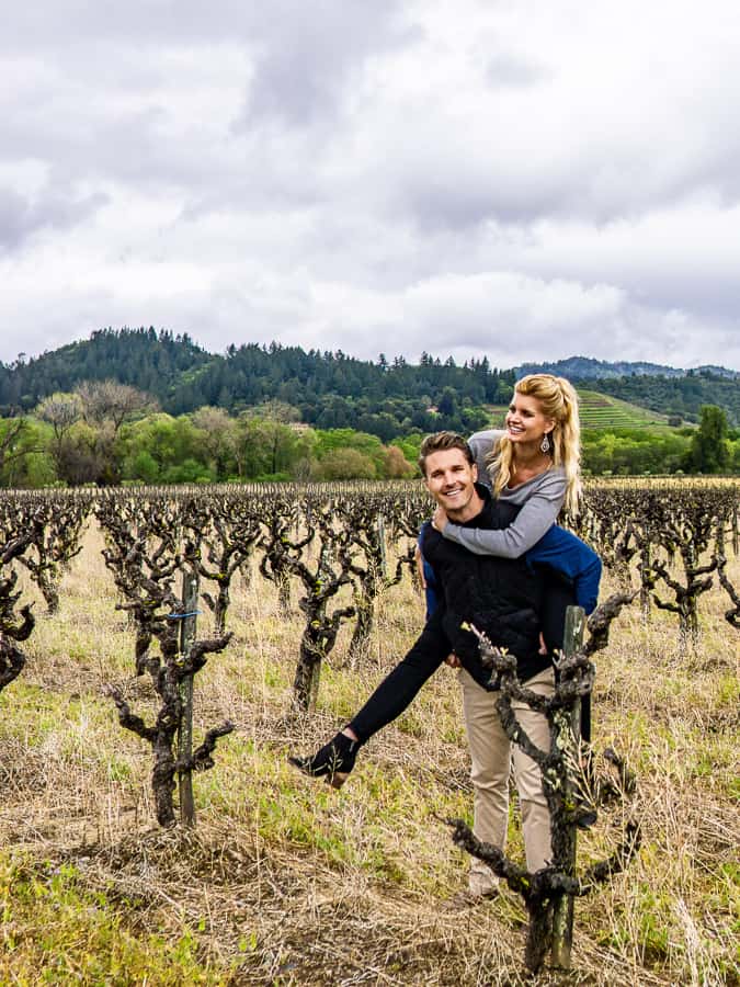 A couple smiling in a field with a mountain behind them.