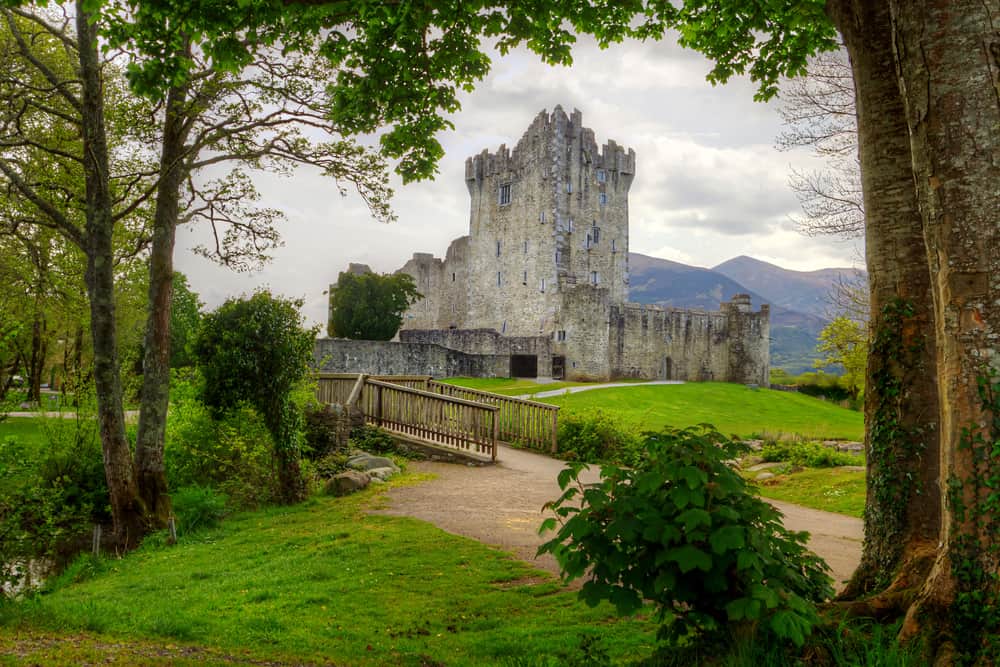 A stone castle in the distance with a small path and bridge leading towards it. 