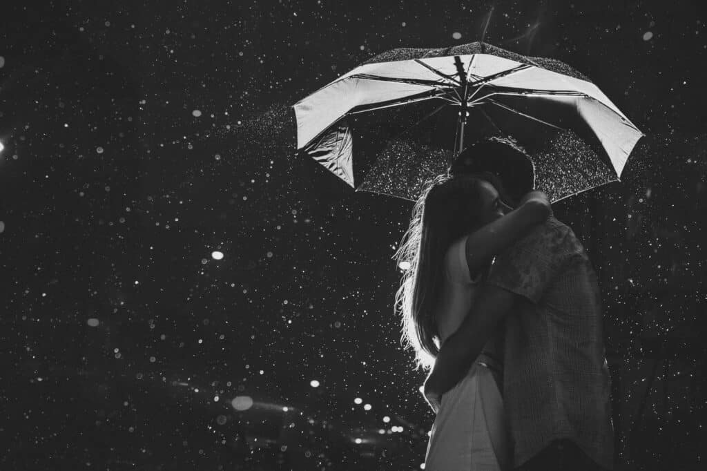 A couple embraces under an umbrella.