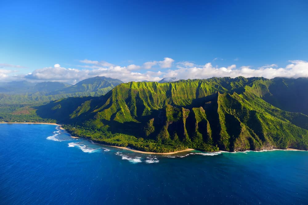 Aerial view of bright green mountains near the ocean.