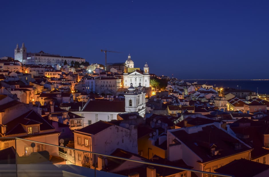 Aerial view of a small city at night with a few of the buildings lit from below. 