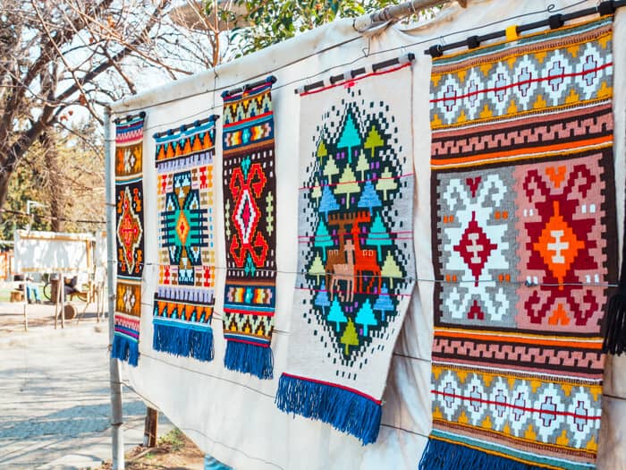 Rugs with bright colors hanging up outdoors.