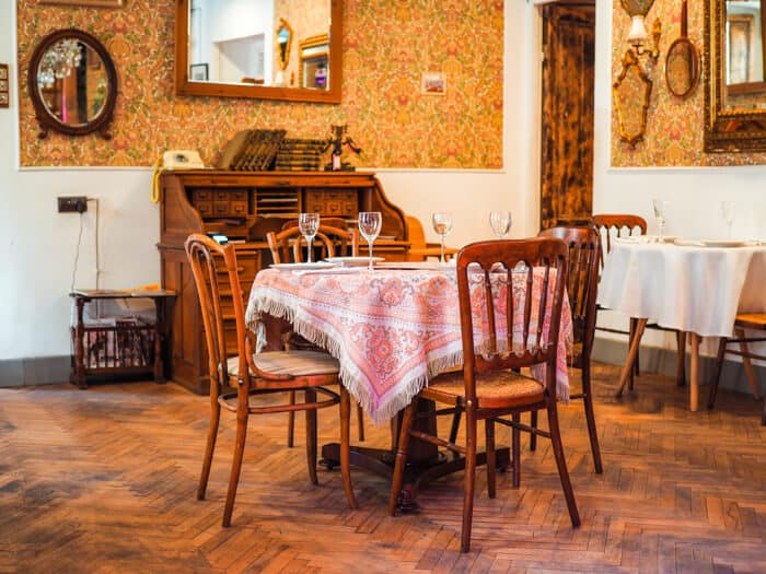 A set table and chairs with wine glasses on it.