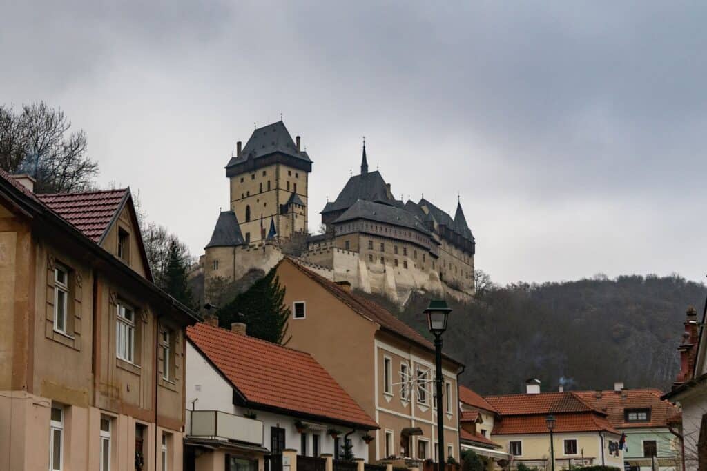 A castle stands up high in a mountain under a grey sky.