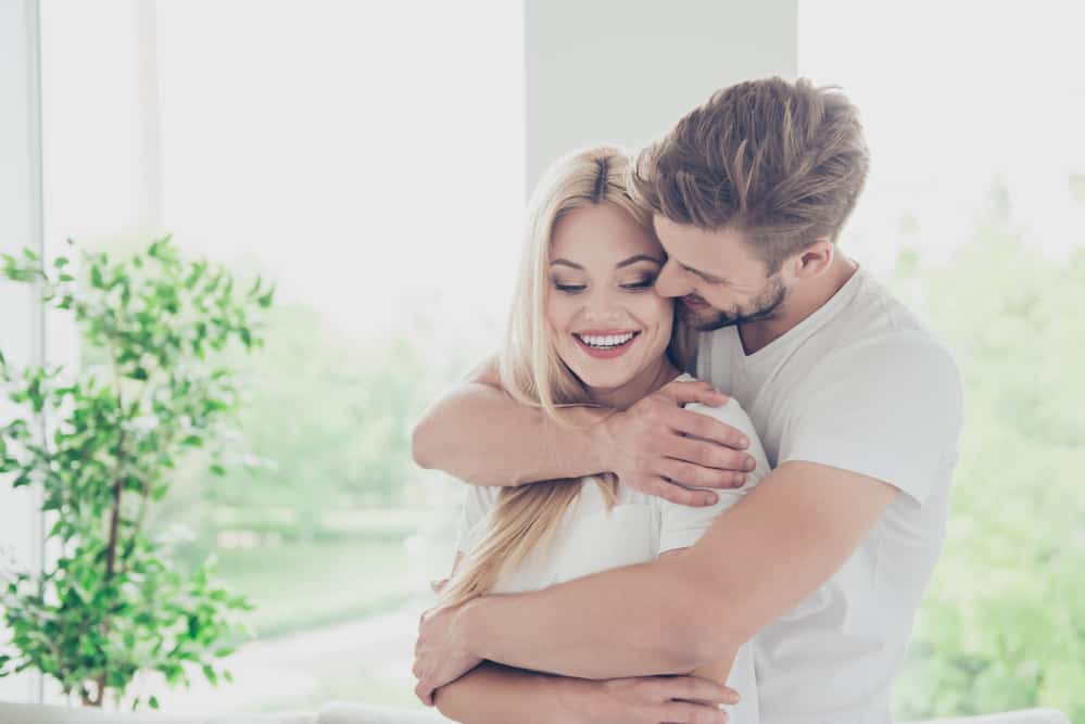 A man embraces a woman from behind.