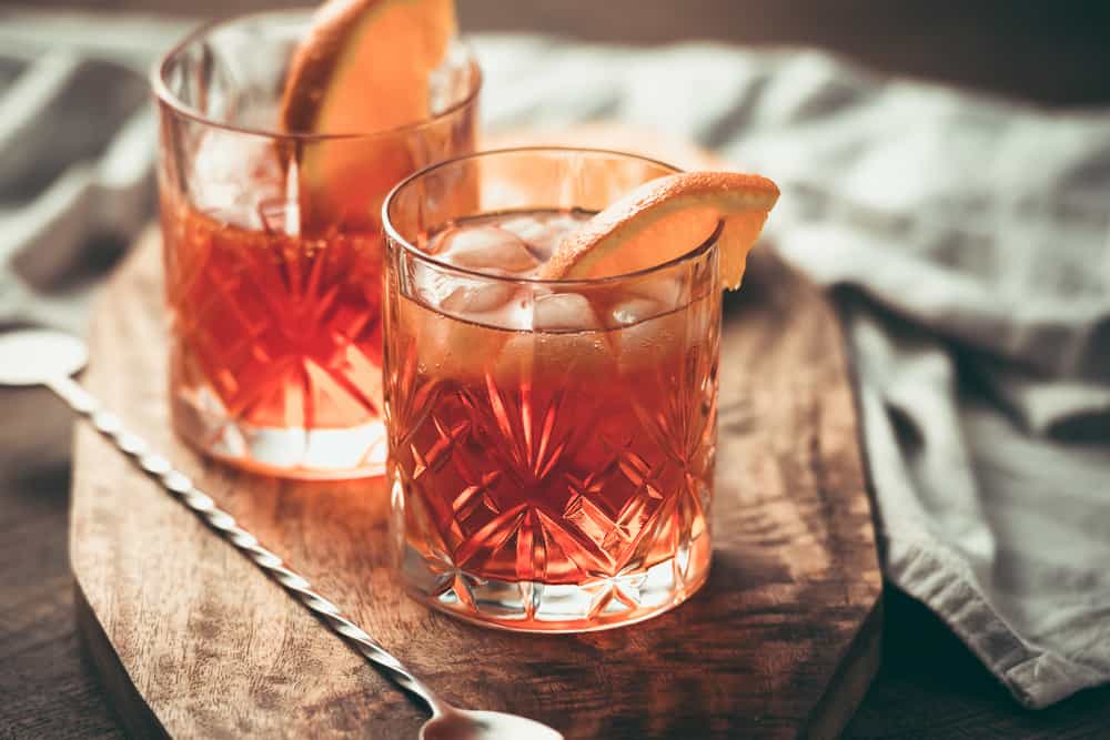 Two glasses of a red drink with fruit on top.