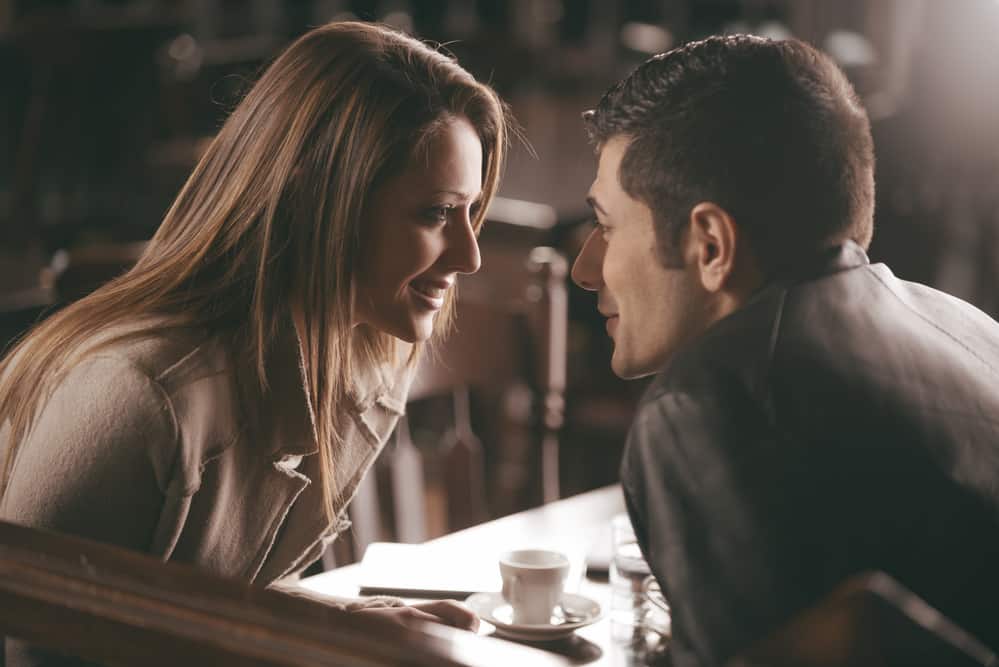 A man and woman are at a bar staring at each other.