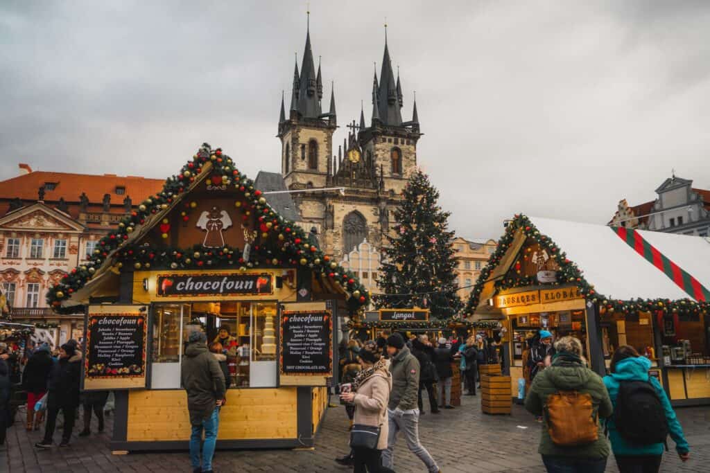 People walking around and shopping at a Christmas market with a church in the background.