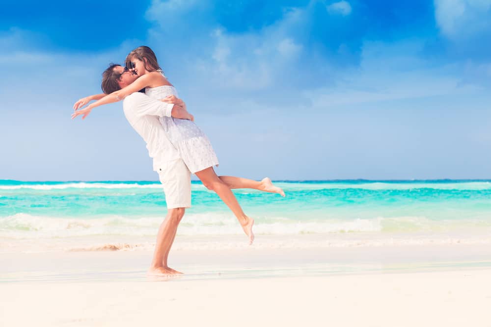 A couple embraces each other on a beach.