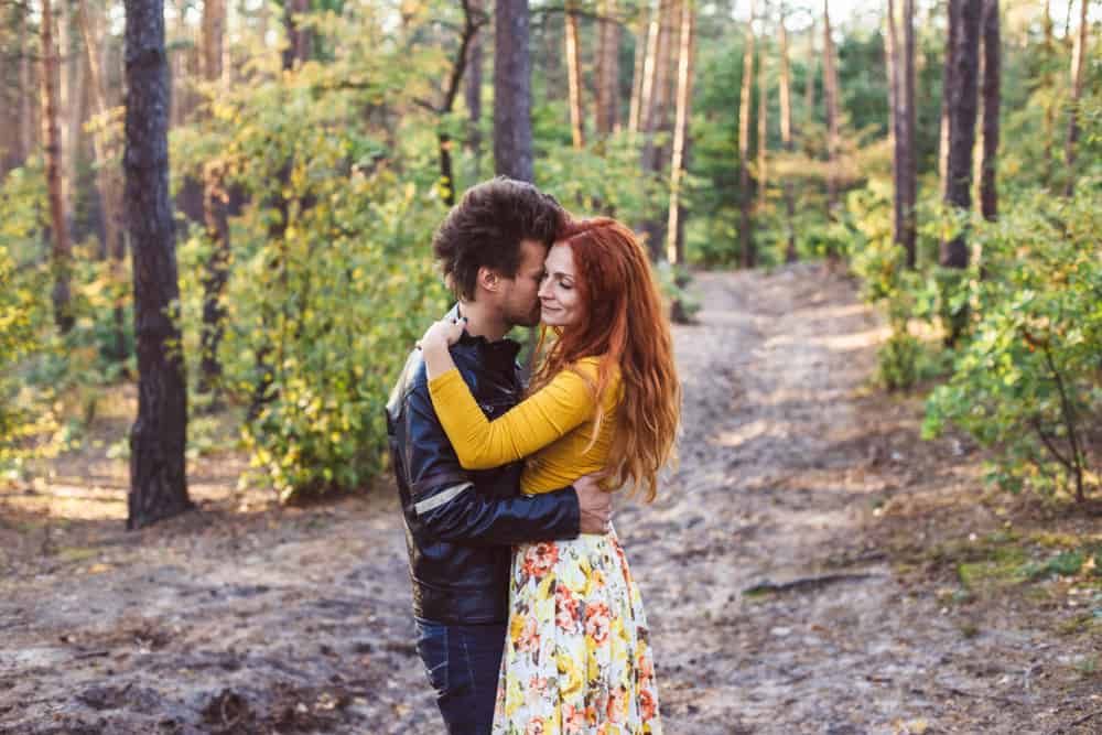 A couple embraces in the forest.