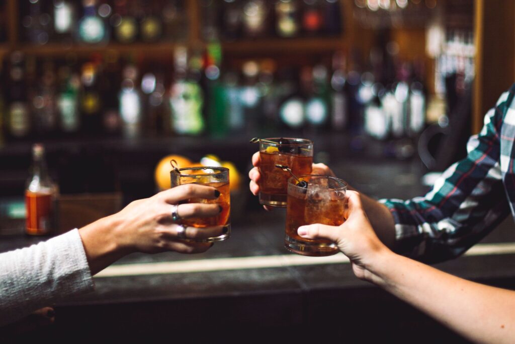 Three people toasting with small alcoholic drinks at the bar.