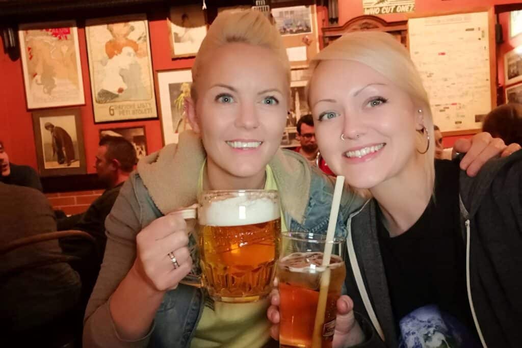 Two woman smiling while holding alcoholic drinks.