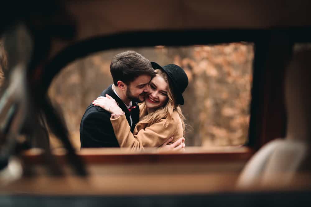 inspirational wedding quotes - Gorgeous newlywed bride and groom posing in pine forest near retro car in their wedding day. image seen through window of car