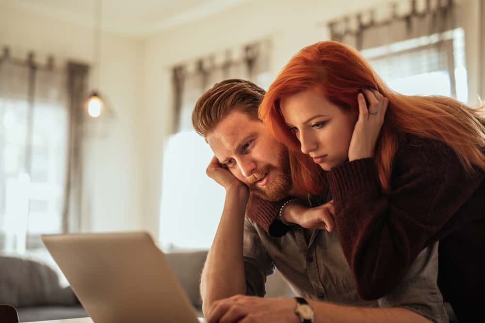 A man and woman hug while looking at a computer.