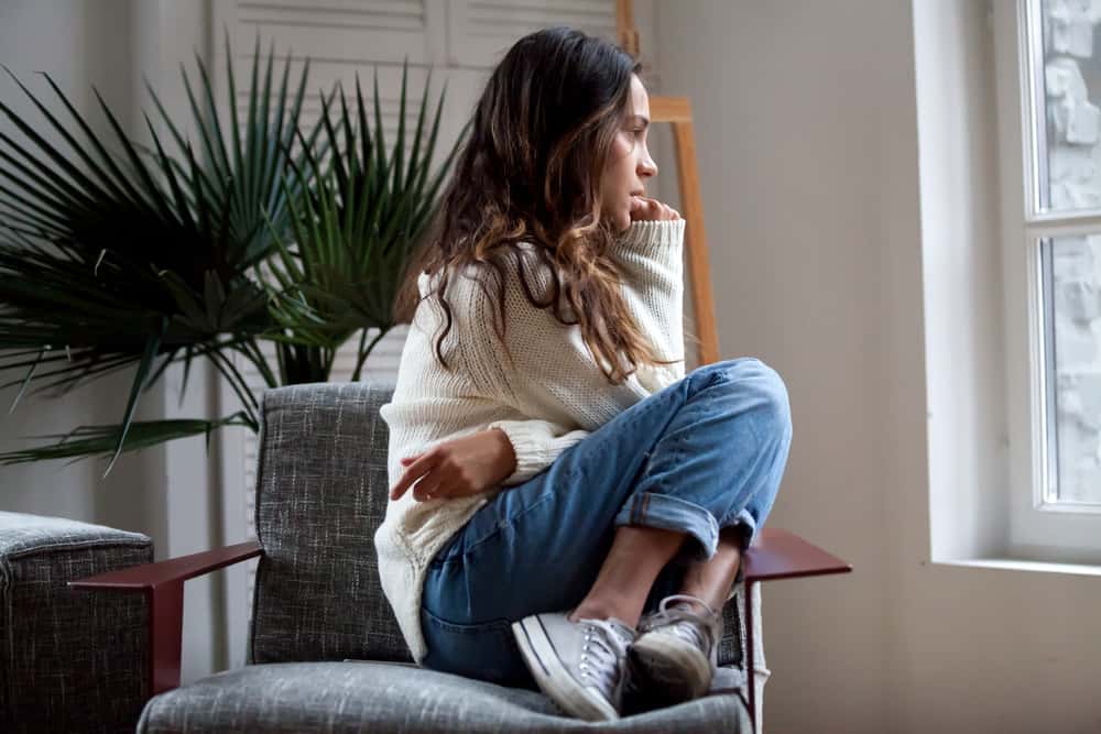 A woman sits in a chair while looking out the window.